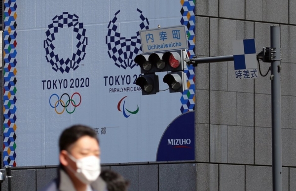 ▲마스크를 쓴 남성이 도쿄올림픽·패럴림픽 홍보물이 설치된 일본 도쿄도(東京都) 지요다(千代田)구의 한 사거리를 지나가고 있다